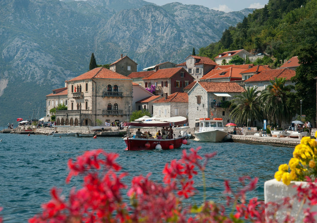 Barca frente a un pueblo de la bahía de Kotor